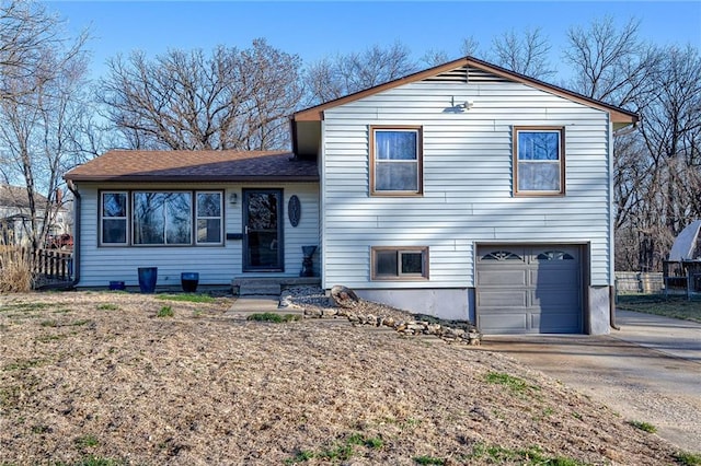 split level home with a garage, driveway, and fence