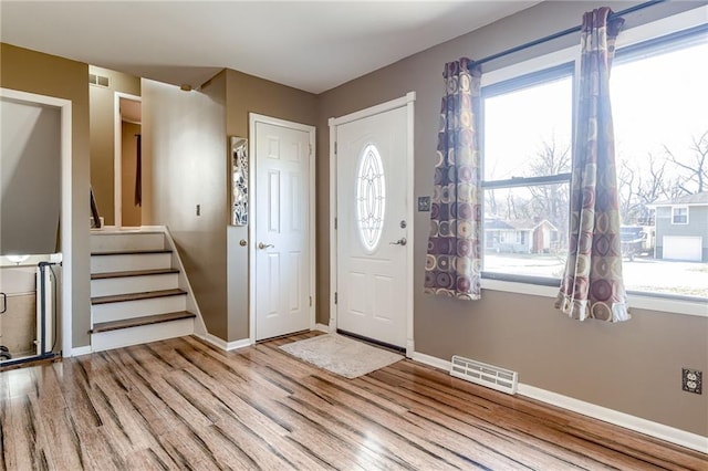 entrance foyer featuring visible vents, baseboards, wood finished floors, and stairway