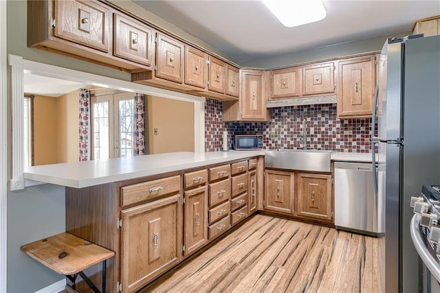 kitchen featuring light countertops, light wood-style flooring, appliances with stainless steel finishes, and a sink