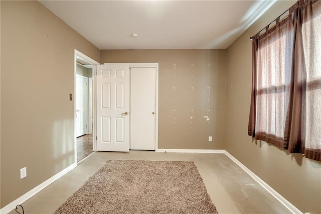 unfurnished bedroom with a closet, baseboards, and concrete floors