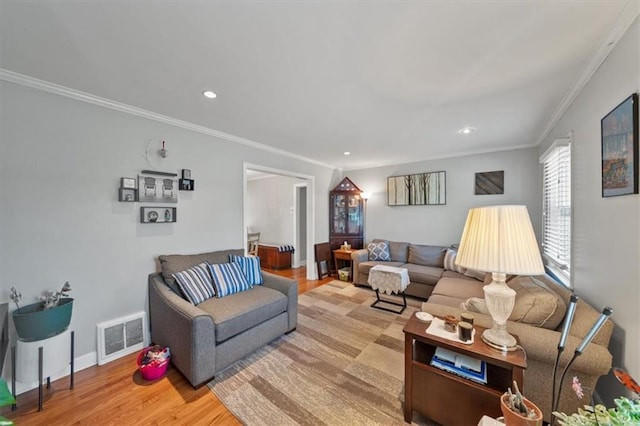 living room featuring wood finished floors, baseboards, visible vents, recessed lighting, and ornamental molding