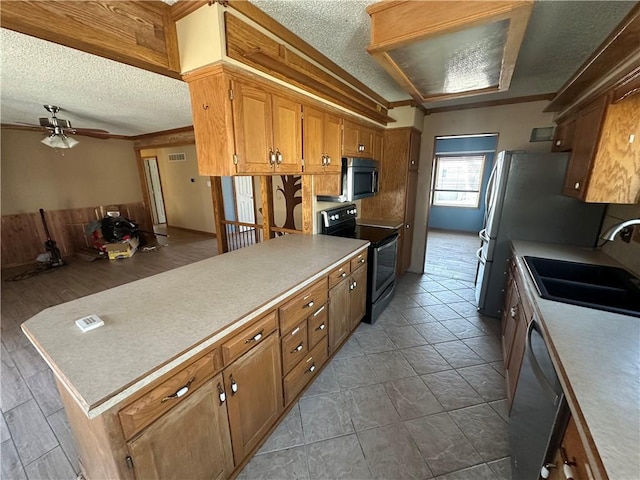 kitchen with a sink, stainless steel appliances, a textured ceiling, and light countertops