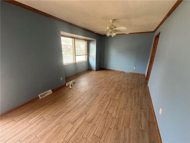 spare room featuring visible vents, crown molding, baseboards, ceiling fan, and light wood-style flooring