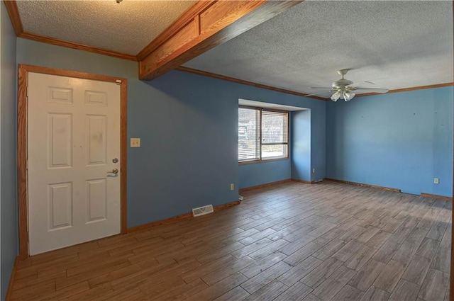 empty room featuring a ceiling fan, a textured ceiling, wood finished floors, and ornamental molding