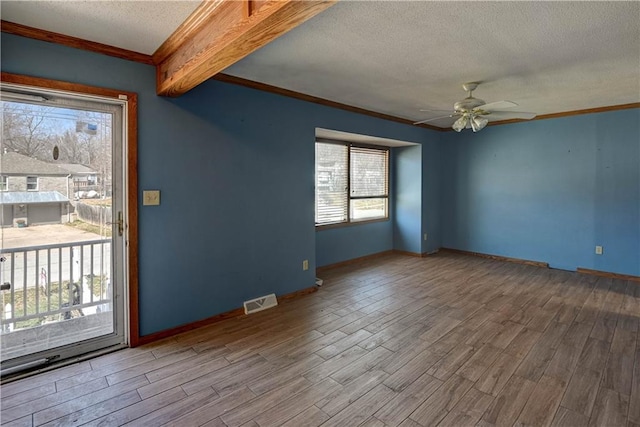 empty room with ceiling fan, visible vents, a textured ceiling, and wood finished floors