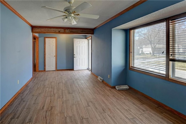 spare room with a ceiling fan, wood finished floors, baseboards, a textured ceiling, and crown molding