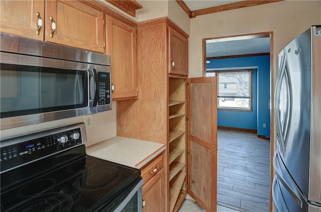 kitchen featuring light wood-type flooring, ornamental molding, a textured ceiling, stainless steel appliances, and light countertops