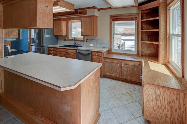 kitchen featuring a sink, appliances with stainless steel finishes, brown cabinetry, and light countertops