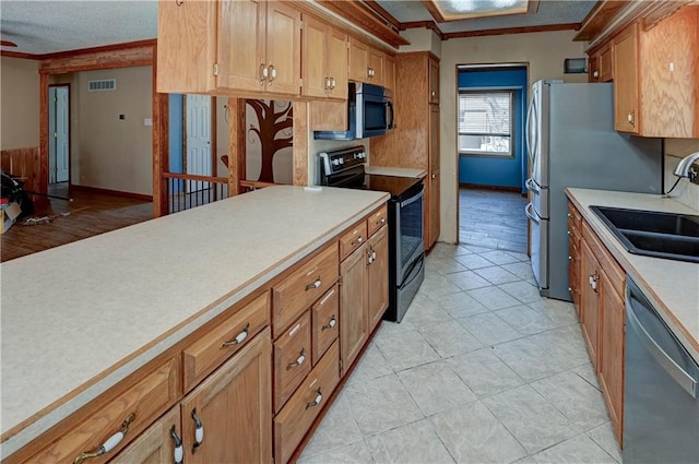 kitchen with visible vents, a sink, appliances with stainless steel finishes, crown molding, and light countertops