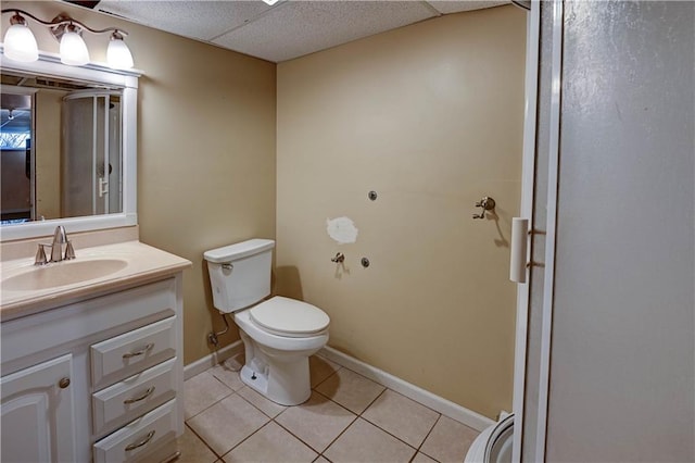 bathroom featuring vanity, baseboards, a paneled ceiling, tile patterned floors, and toilet