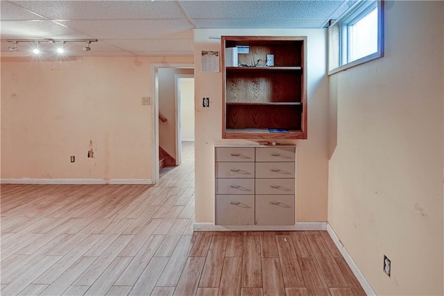 spare room featuring track lighting, wood finished floors, baseboards, and a drop ceiling