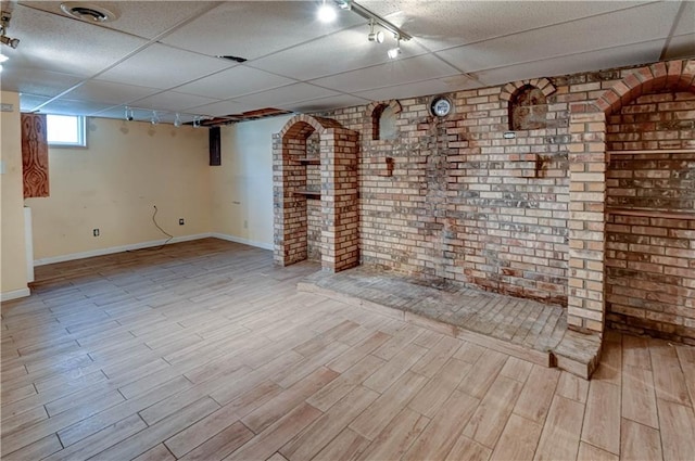 basement with rail lighting, wood finished floors, visible vents, and a paneled ceiling