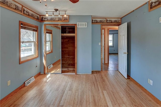 unfurnished bedroom featuring crown molding, wood finished floors, visible vents, and a textured ceiling