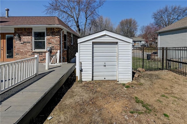 garage featuring fence and a shed