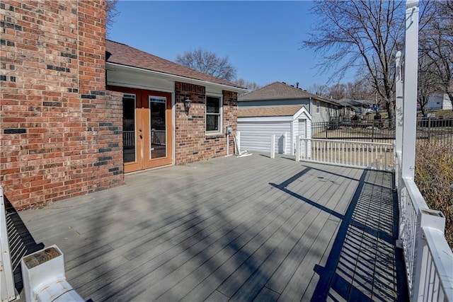 wooden terrace with an outbuilding, french doors, and fence