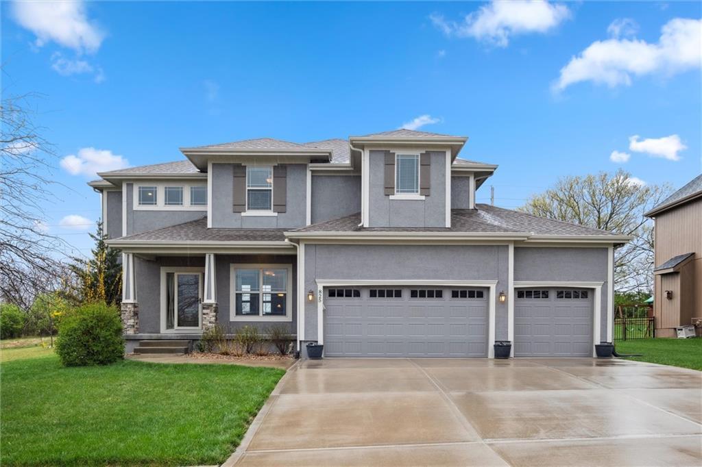 prairie-style house with driveway, stucco siding, a front lawn, and a garage
