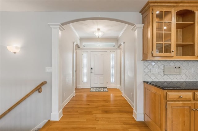 interior space with arched walkways, decorative columns, light wood-style floors, and ornamental molding