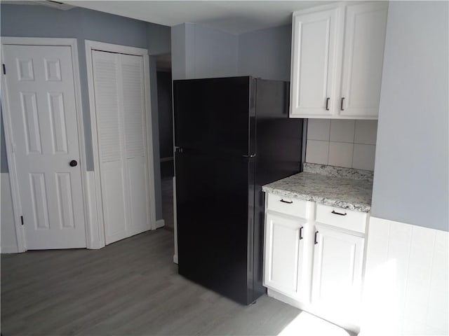 kitchen featuring light wood finished floors, white cabinets, freestanding refrigerator, and backsplash