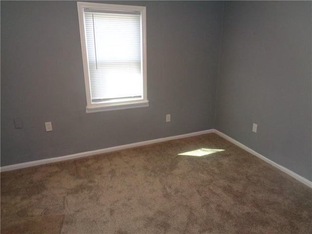 carpeted spare room featuring baseboards