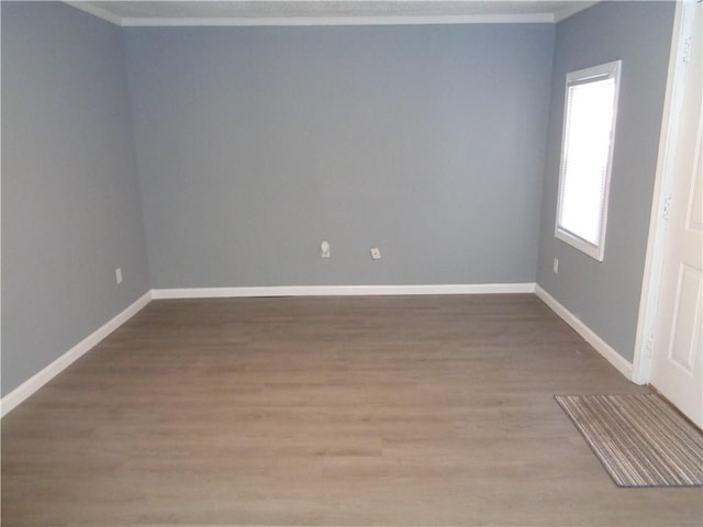 unfurnished room featuring crown molding, baseboards, and wood finished floors