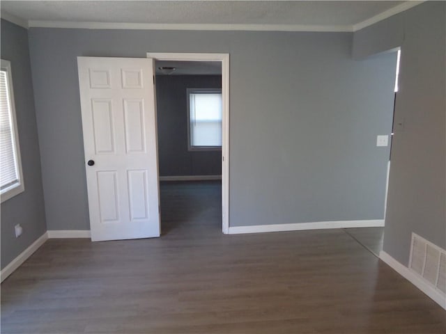 unfurnished room featuring visible vents, a textured ceiling, dark wood finished floors, crown molding, and baseboards