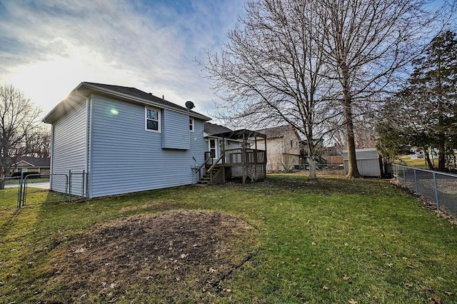 rear view of property with a gate, a fenced backyard, an outdoor structure, a deck, and a lawn