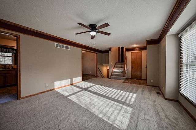 unfurnished living room with visible vents, crown molding, carpet, stairway, and a sink