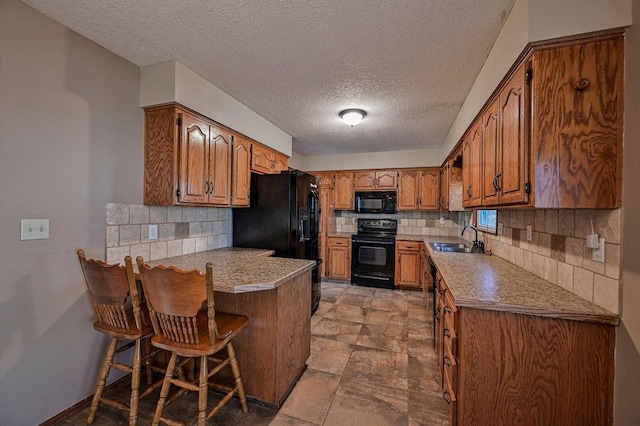 kitchen with a sink, brown cabinets, black appliances, and a peninsula