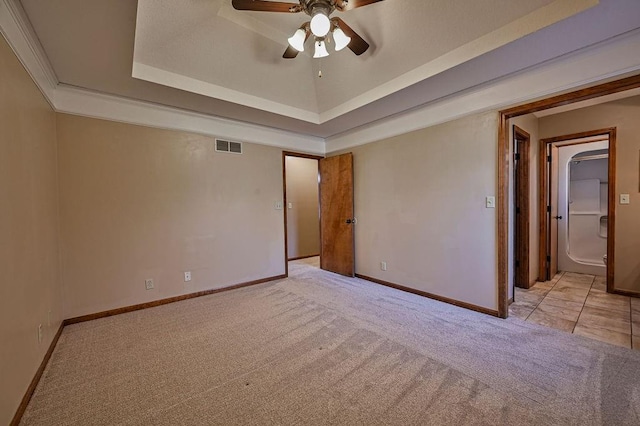 empty room featuring a tray ceiling, visible vents, baseboards, and carpet floors