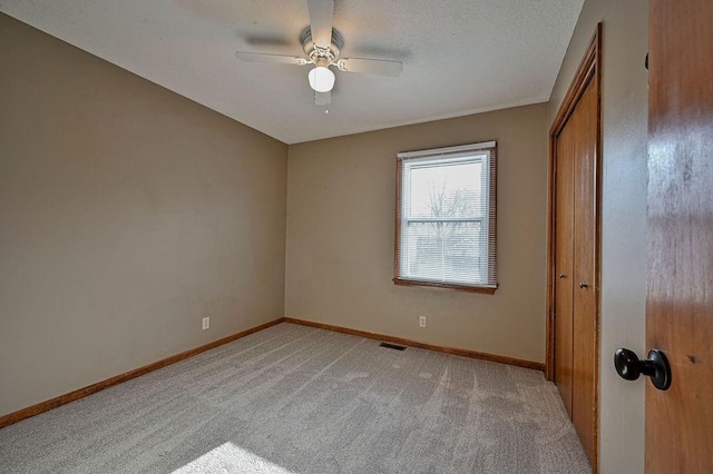 unfurnished bedroom featuring visible vents, light colored carpet, a closet, and baseboards