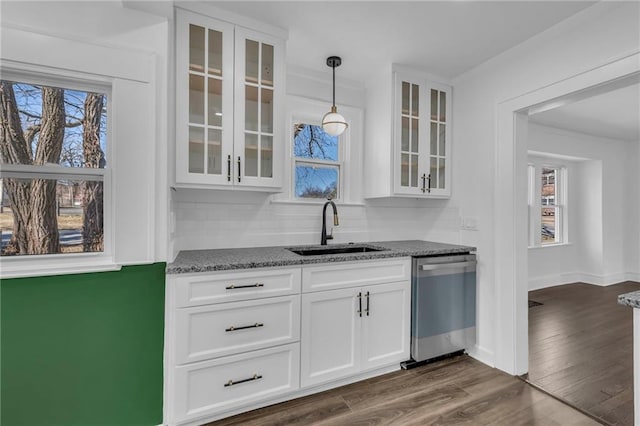 interior space with white cabinets, dishwasher, stone countertops, and a sink