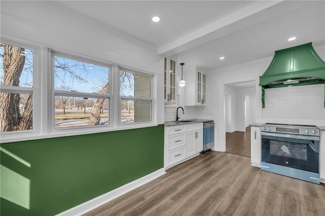 kitchen with dark wood-style floors, stainless steel appliances, custom exhaust hood, white cabinetry, and a sink