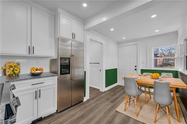 kitchen with stainless steel appliances, tasteful backsplash, wood finished floors, and white cabinetry