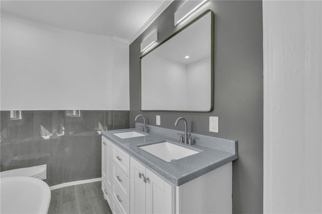 full bathroom featuring tile walls, toilet, wood finished floors, and a sink