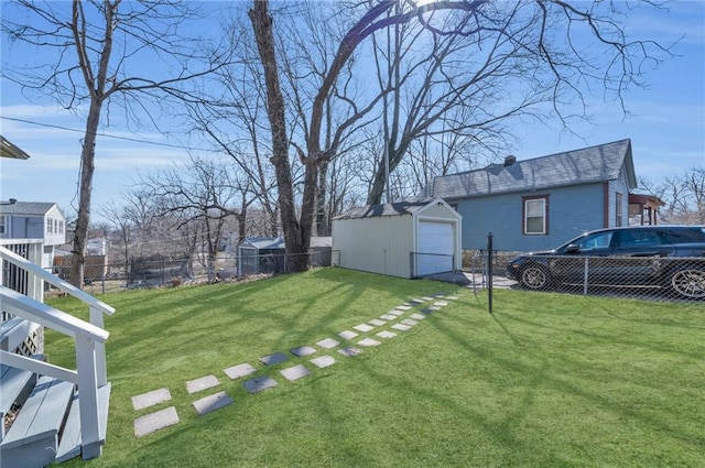 view of yard featuring a detached garage, a fenced backyard, driveway, and an outbuilding