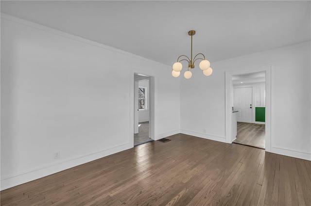 unfurnished room featuring baseboards, wood-type flooring, a chandelier, and crown molding