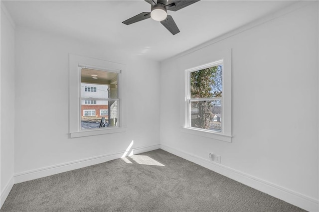 carpeted empty room featuring baseboards and a ceiling fan