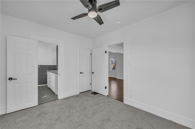 unfurnished bedroom with ensuite bath, baseboards, carpet floors, and ornamental molding