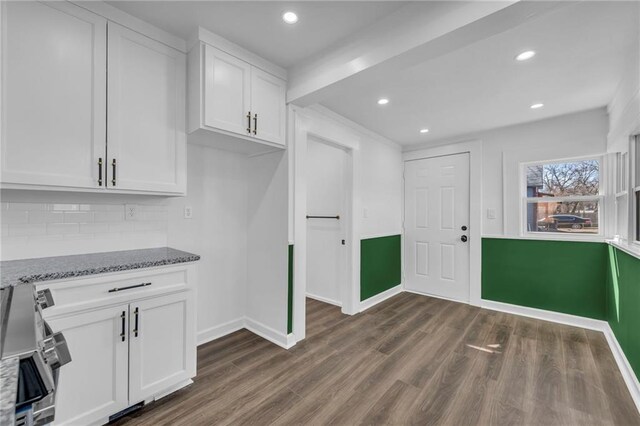 1901 E 79th St, Kansas City, MO 64132 - kitchen with dark wood-type flooring, light stone counters, tasteful backsplash, white cabinetry, and baseboards
