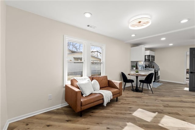 living area with recessed lighting, visible vents, light wood-style flooring, and baseboards