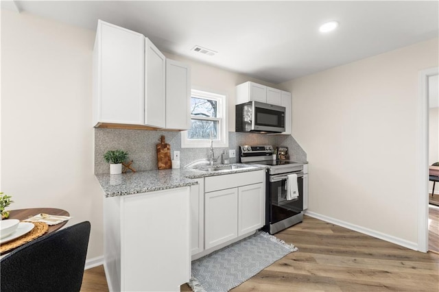 kitchen with visible vents, backsplash, light wood-type flooring, stainless steel appliances, and a sink