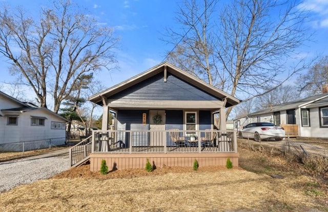 bungalow-style home with a porch and gravel driveway