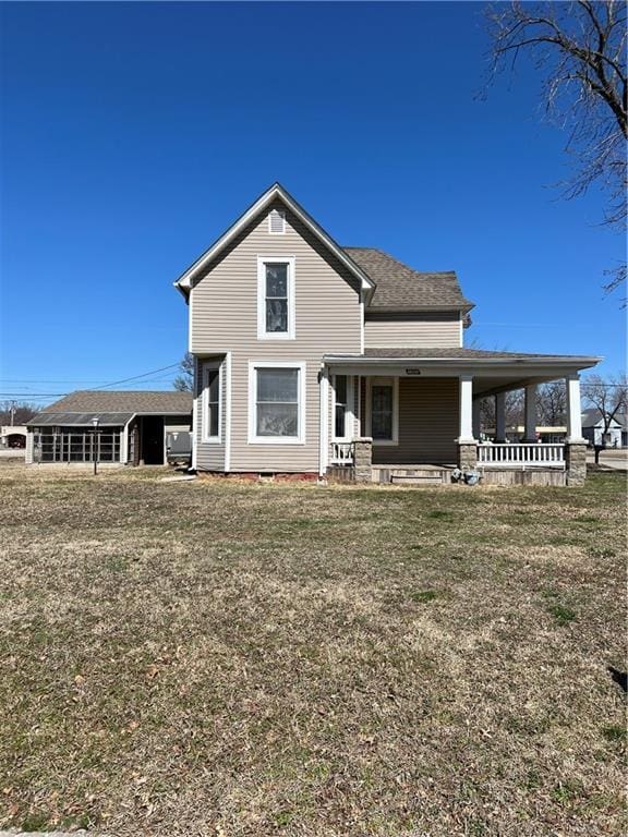 back of property featuring a yard and covered porch