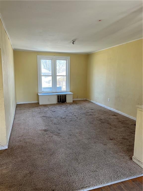 carpeted empty room featuring visible vents, baseboards, and crown molding