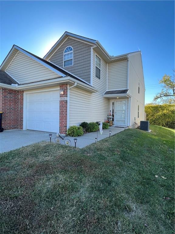 traditional home featuring a front yard, an attached garage, central AC unit, and brick siding