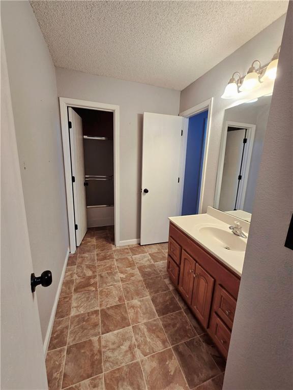 bathroom with vanity, baseboards, and a textured ceiling