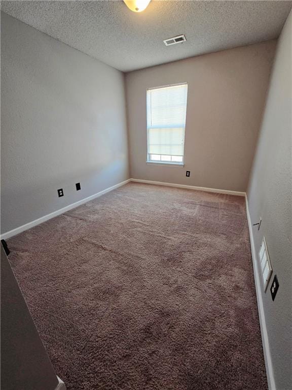 carpeted empty room with baseboards, visible vents, and a textured ceiling