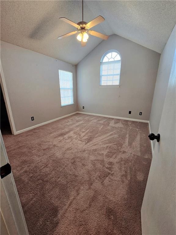 unfurnished room with baseboards, lofted ceiling, ceiling fan, a textured ceiling, and carpet flooring