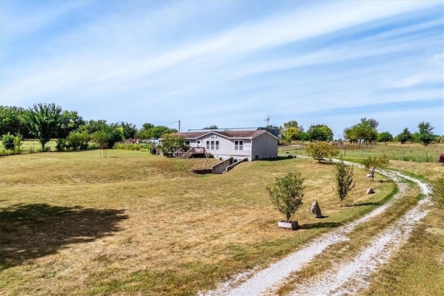 view of yard with driveway and a view of rural / pastoral area