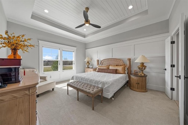 bedroom with a tray ceiling, ornamental molding, light carpet, wooden ceiling, and a decorative wall